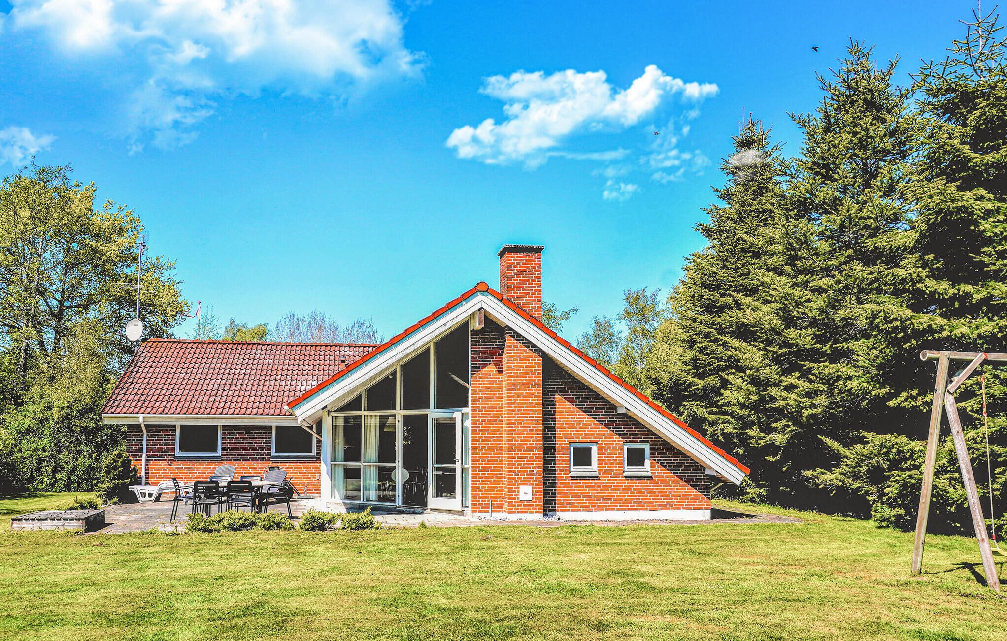 Et moderne hus med skråt tag, store vinduer og facade i mursten.