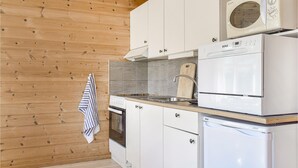A compact kitchen with white cabinets, a built-in oven, a microwave, and a sink. - 2 bedroom beach front home in Vallavik (Vallavik)