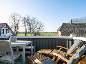 Eine Terrasse im Freien mit Tisch und Stühlen, einer dekorativen Kugel und Blick auf Häuser und Bäume im Hintergrund.