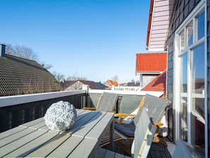 Eine Holzterrasse mit einer weißen Dekorationsvase, einem Holzstuhl und einem Tisch.