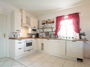A kitchen with white cabinets, a microwave, an oven, and a sink.