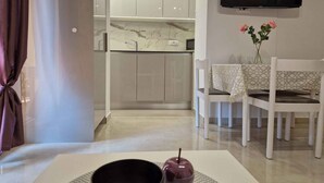 Una cocina moderna con encimeras de mármol, un comedor con mesa y sillas, y un televisor de pantalla plana montado en la pared.