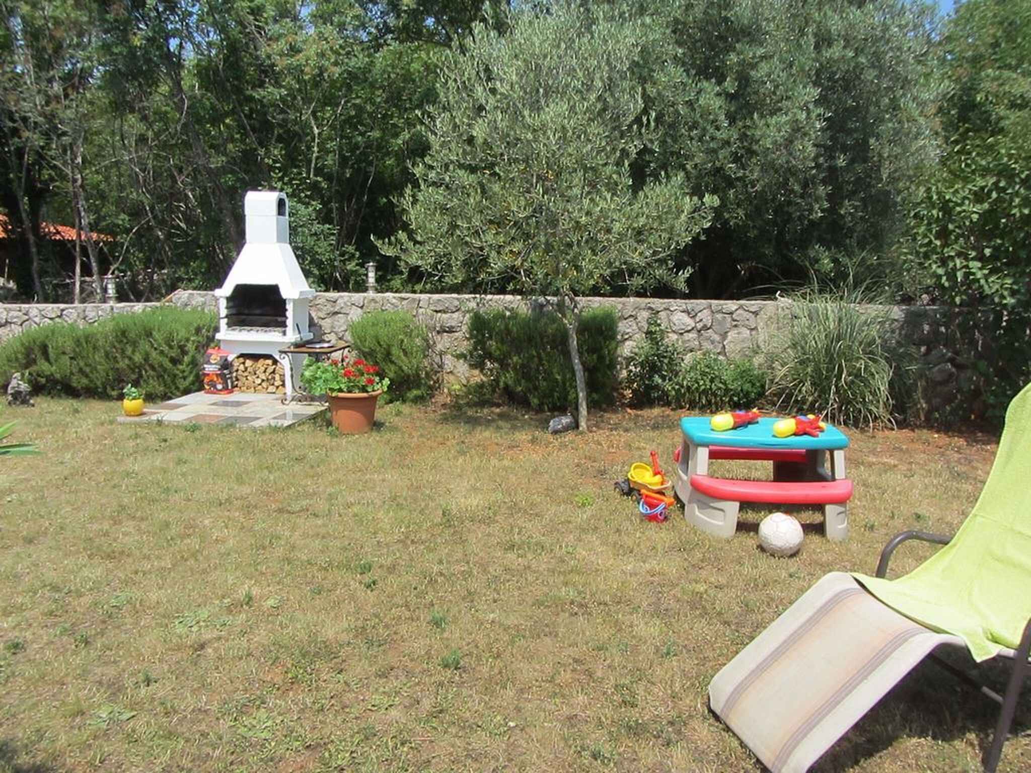 Un jardin avec un barbecue, une table pour jouer et une chaise de jardin.