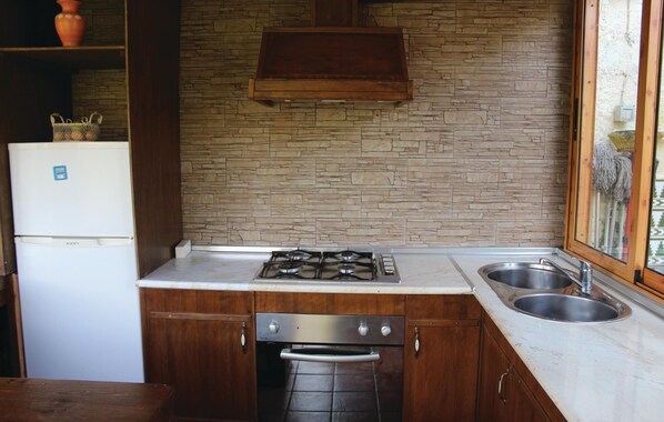 A compact kitchen with a stone backsplash, a built-in oven, a gas stove, and a stainless steel sink. - Cozy home in Nerja with WiFi (Nerja)