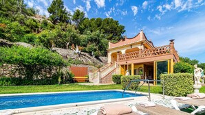 A poolside area with a pool, a building with a tiled roof, and a staircase leading to the building. - Cozy home in Nerja with WiFi (Nerja)