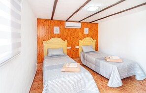 A room with two single beds, wooden panel walls, a ceiling fan, and an air conditioning unit. - Cozy home in Nerja with WiFi (Nerja)