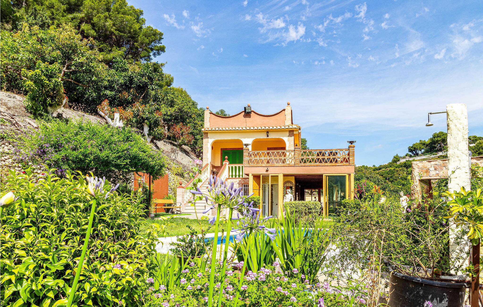 Eine mediterrane Villa mit terrassenförmig angelegtem Garten, einem Pool und Blick auf die umliegenden Hügel.