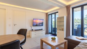 Ein modernes Wohnzimmer mit Esstisch, einer Couch, einem Fernseher und einer Glasvitrine.