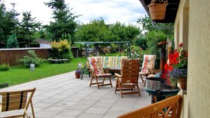 An outdoor patio with wooden furniture, a table, and a hanging basket. - Vacation cottage Ursula - Holiday cottage (Malchow)