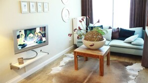 A living room with a television, a wooden coffee table with a plant, a sofa, and a cowhide rug. - (252) 2-room apartment - apartment complex holiday dreams (Kühlungsborn)