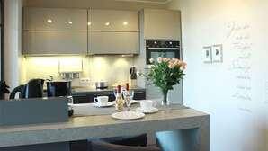 A modern kitchen with a central island, built-in appliances, and a decorative wall with text. - (252) 2-room apartment - apartment complex holiday dreams (Kühlungsborn)
