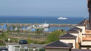 A coastal view with a marina, boats, and a row of houses with sloped roofs. - (252) 2-room apartment - apartment complex holiday dreams (Kühlungsborn)