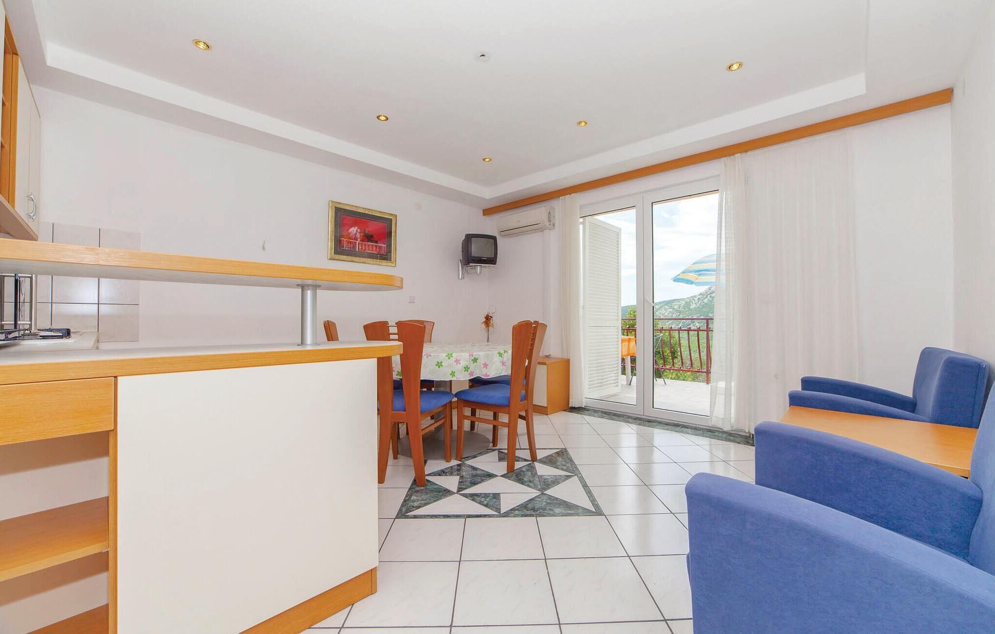 Un espace de vie compact comprenant un coin repas, une kitchenette et un balcon avec vue.