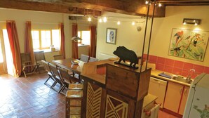 A rustic kitchen with a wooden island, a dining area with chairs, and a kitchen counter with a sink and a refrigerator.