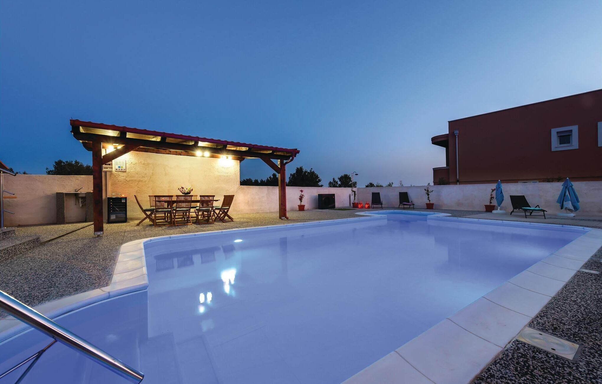 Ein Schwimmbad mit überdachtem Patio, Sitzgelegenheiten im Freien und einem Gebäude im Hintergrund.
