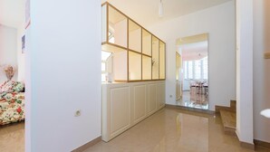 A hallway with a glass partition, a dining area with chairs and a table, and a floral-patterned sofa. - Gorgeous home in Brodarica (Brodarica)