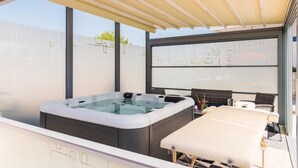 A modern outdoor hot tub area with a covered seating area and a view of the cityscape. - Gorgeous home in Brodarica (Brodarica)