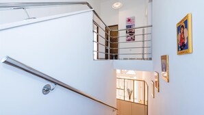 A modern staircase with metal railings and a handrail, leading to a second-floor landing with a glass door. - Gorgeous home in Brodarica (Brodarica)