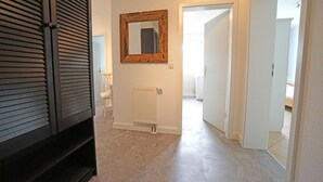 Ein Flur mit Heizkörper, einem spiegelnden Holzbruch und einer weißen Tür zu einem weiteren Raum.