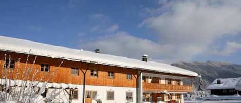 Ein großes Holzgebäude mit verschneitem Dach, umgeben von Schnee.
