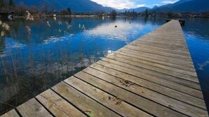 Een houten steiger die uitloopt in een rustig meer, met bergen op de achtergrond.