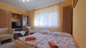 A bedroom with a bed, a TV, a desk, and a chair.
