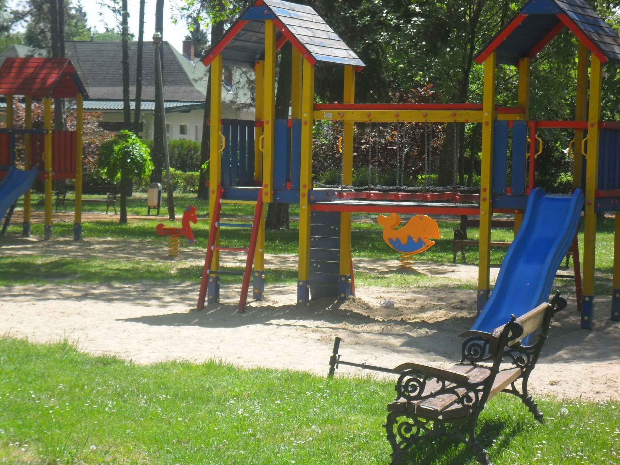 Un parc infantil amb tobogan, elements per escalar i una cadira.