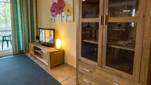 Een kamer met een houten kast, een televisie op een houten dressoir, en een schilderij aan de muur.