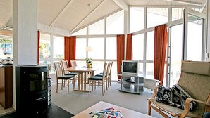 Ein geräumiger Wohnbereich mit Kamin, einem Esstisch mit Stühlen, einem Fernseher und einer Couch.
