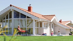 Ein Haus mit einer großen Veranda, einem roten Ziegeldach und einem Schornstein.