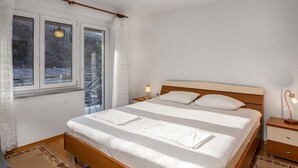 A bedroom with a wooden bed, white linens, a nightstand with a lamp, and a window with curtains. - 2 bedroom gorgeous apartment in Knezica (Knezica)