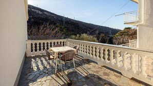 A balcony with a stone floor, a table, and two chairs. - 2 bedroom gorgeous apartment in Knezica (Knezica)