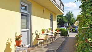 A yellow building with a balcony, outdoor seating, and potted plants. - Vacation apartment 03 with sea view - Strandhaus Göhren 100 m to the beach! (Göhren)
