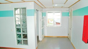 Un pasillo con una ventana, una puerta y un objeto rojo en la pared.