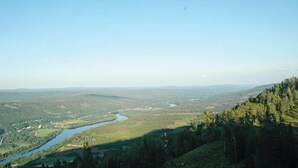 Vista panorámica de un valle con un río, rodeado de bosques densos y colinas.