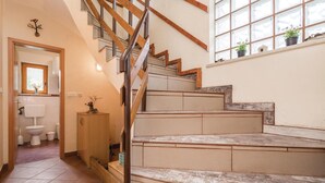 Eine Treppe mit Holzgeländern und Blick auf ein Badezimmer mit Toilette und Schrank.