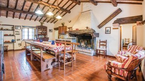 A rustic kitchen with a large wooden table, a fireplace, and a dining area with chairs. - Amazing home in Arcidosso GR (Arcidosso GR)