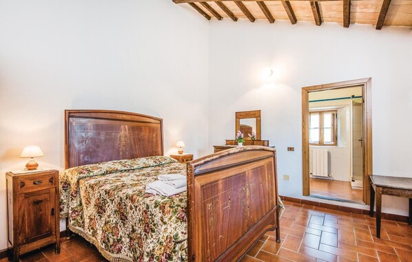Un dormitorio con una cama de madera, una mesita de noche, un aparador y un espejo.