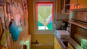 A compact kitchen with wooden cabinets, a window with a view, and a small countertop.