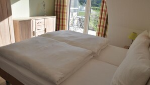A neatly made bed with white linens in a room with a view of a garden through a window. - Stunning apartment in Kaschow with WiFi (Kaschow)