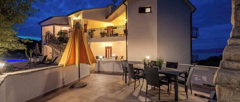 Een gebouw met twee verdiepingen, een terras, zitplaatsen buiten en een zwembad.