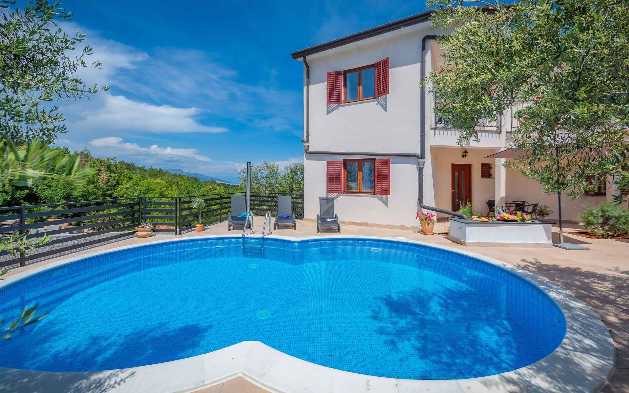 A two-story building with a swimming pool, outdoor seating, and a view of a lush green landscape.