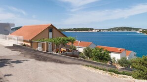 Une propriété située sur la côte, avec un toit recouvert de tuiles rouges, une façade blanche et une vue sur la mer.