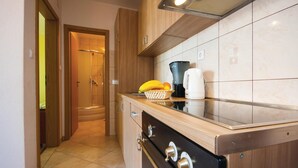 Une cuisine équipée d’une cuisinière, d’une machine à café et d’un panier de fruits posé sur le comptoir.