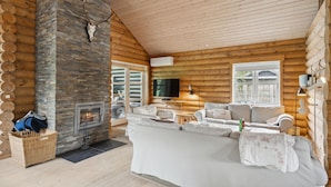 A log cabin interior with a stone fireplace, a television, and a cozy seating area. - Lovely home in Stege with sauna (Stege)