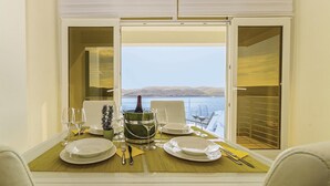 Une table à manger dressée pour deux personnes, avec vue sur un lac et des collines.