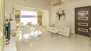 Un salon moderne avec un canapé blanc, une table à manger et des chaises, ainsi qu’une grande fenêtre donnant sur les montagnes.