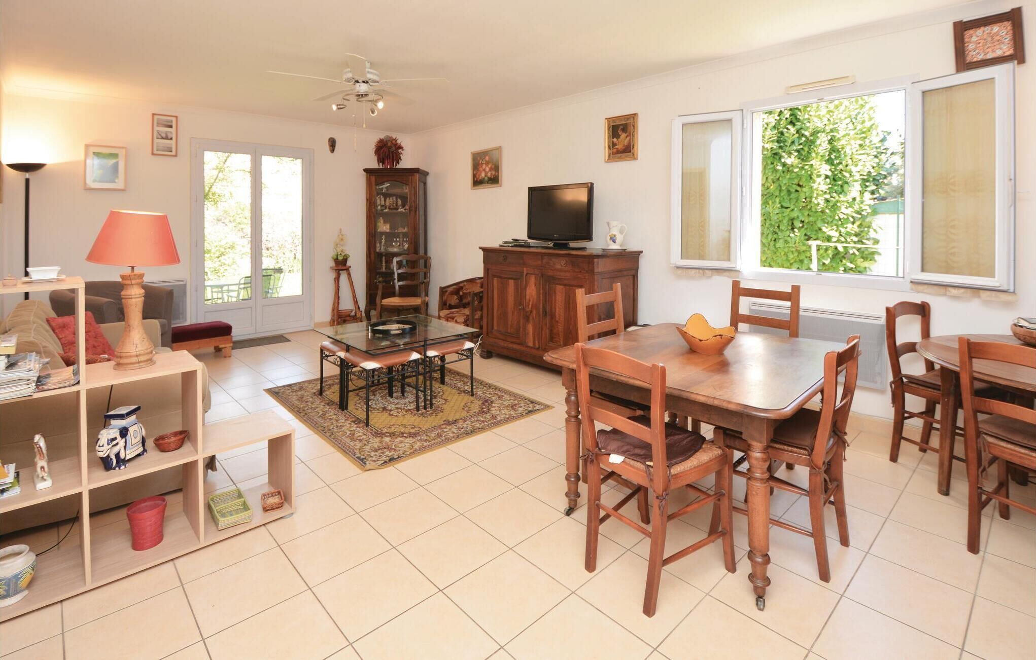 Un salon spacieux comprenant un coin repas, un téléviseur et une grande fenêtre donnant sur un paysage verdoyant.