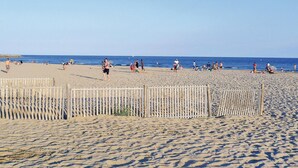 A sandy beach with wooden fences and people engaging in various activities.