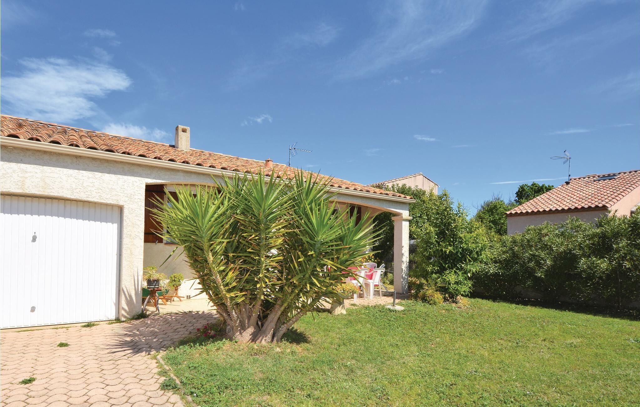 Une maison avec un toit en tuiles, un portail de garage et une pelouse bien entretenue.